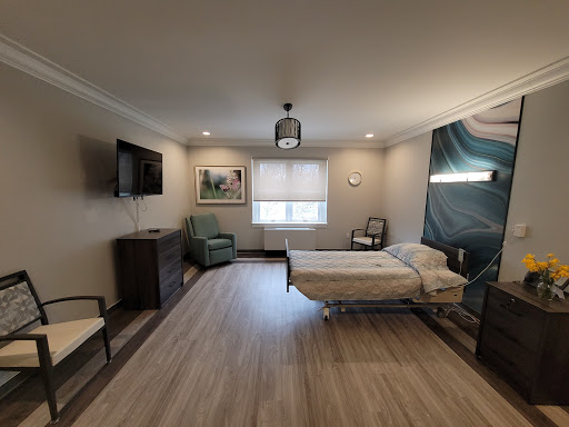 A well-lit and modern hospital patient room featuring a bed, TV, and seating area.
