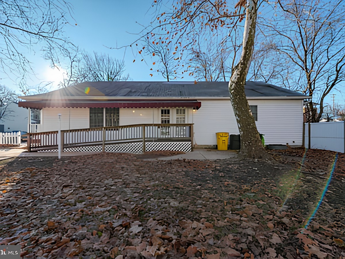 A house with a ramp in the backyard surrounded by trees and autumn leaves.