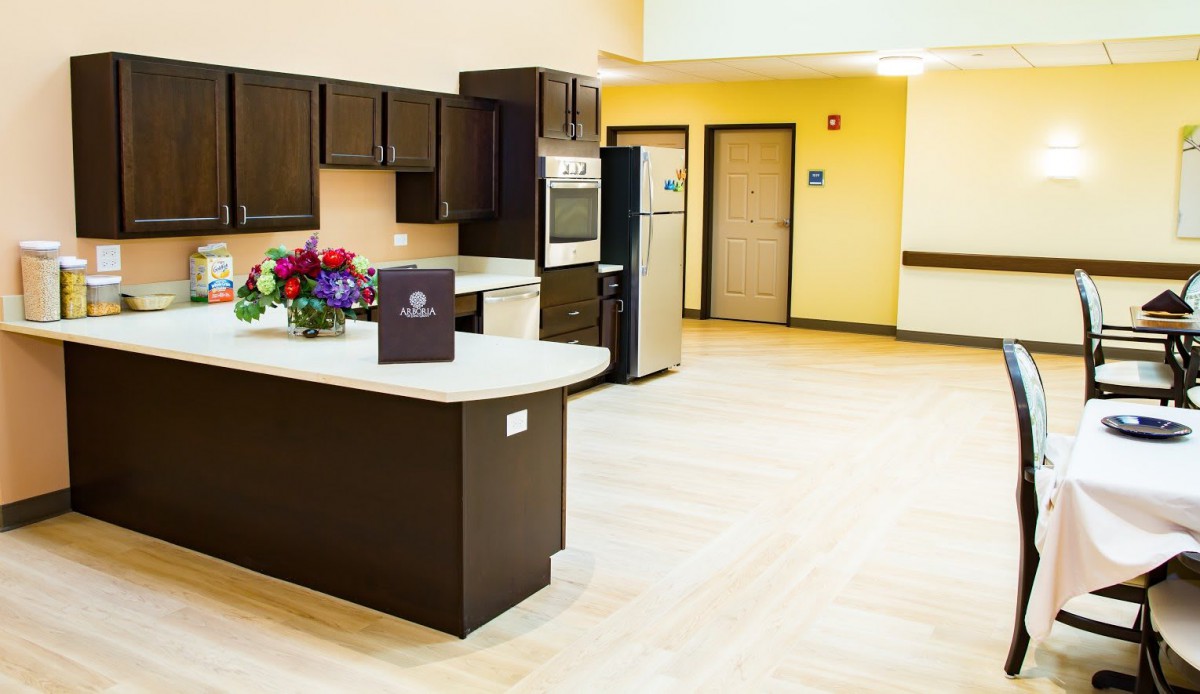 A modern kitchen with dark cabinets, stainless steel appliances, and a light countertop, adorned with a bouquet of flowers.