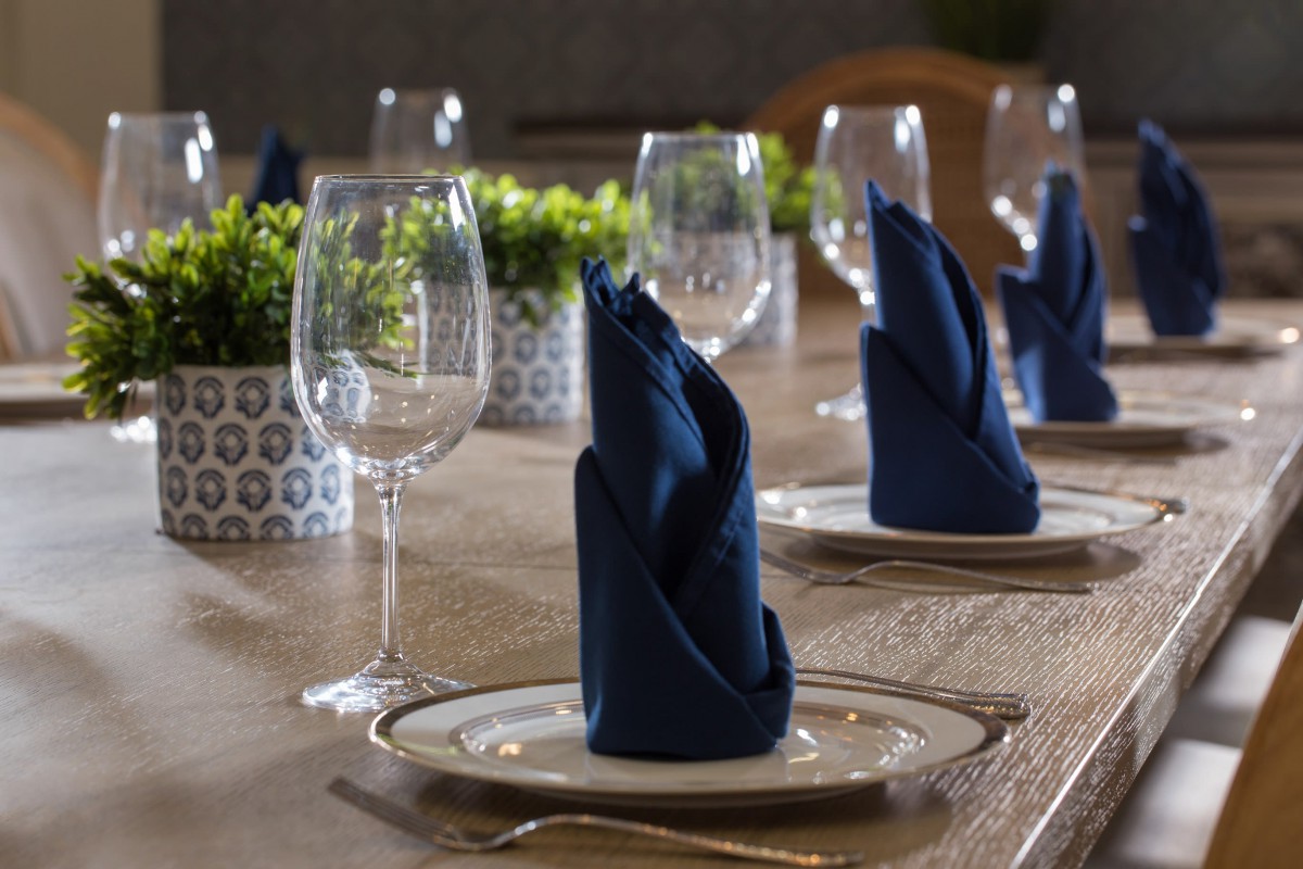 A neatly arranged table setting with blue napkins and wine glasses.