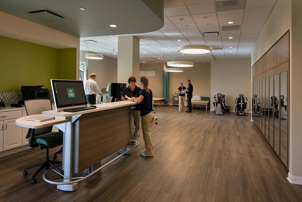 A modern office reception area with people interacting at the desk.