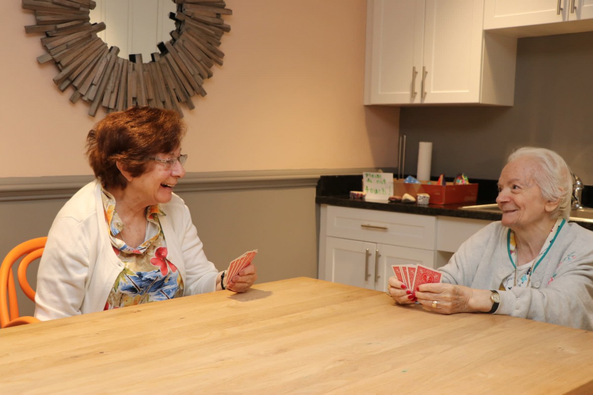 Two elderly women enjoying a game of cards in the kitchen.