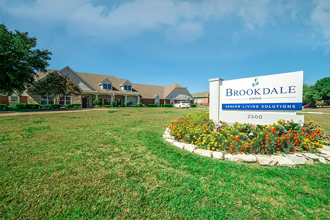 A building with a landscaped lawn and signage in front.