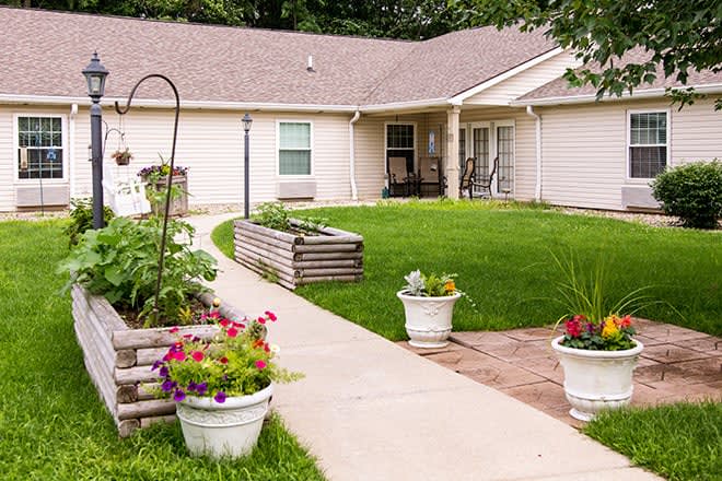A cozy home with a well-maintained garden, featuring lush green lawn and colorful flower planters along the pathway.