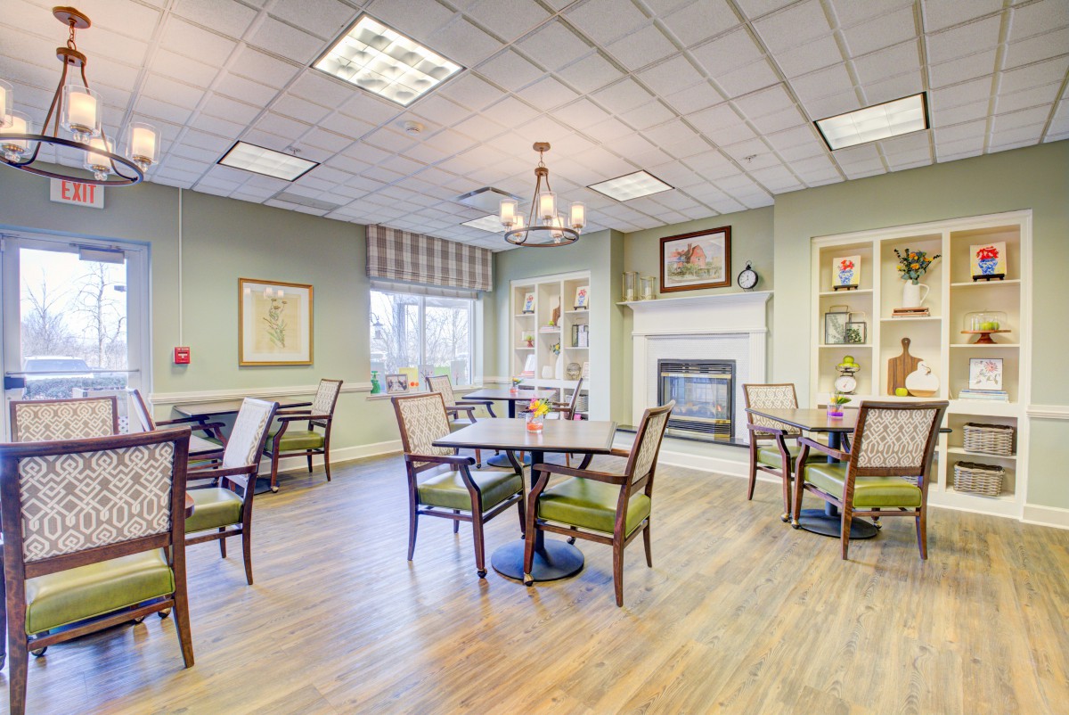 A cozy dining area featuring multiple tables and chairs, a fireplace, and a chandelier.
