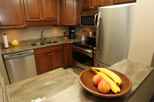 A cozy kitchen featuring wooden cabinets, modern appliances, and a bowl of fresh fruits.