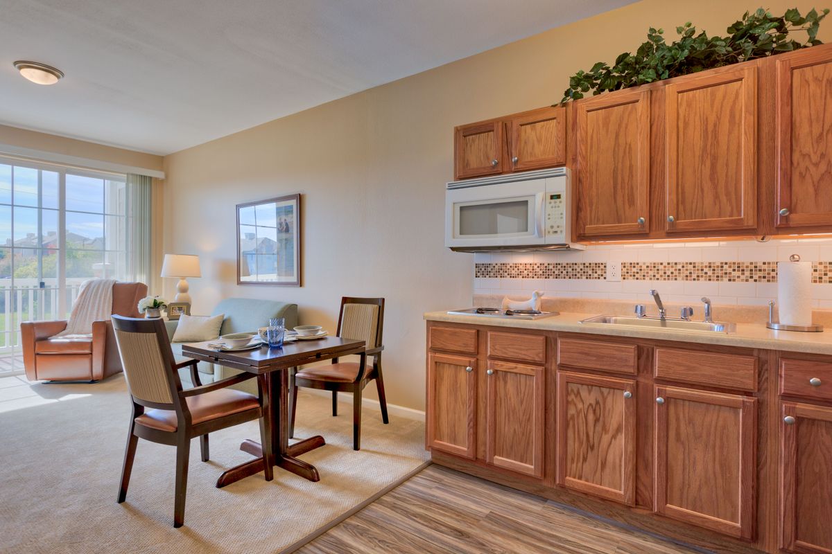 A cozy kitchen and dining area featuring wooden cabinets, a small table with chairs, and standard appliances.