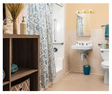 A cozy bathroom with a patterned shower curtain, sink, mirror, and decorative shelving.