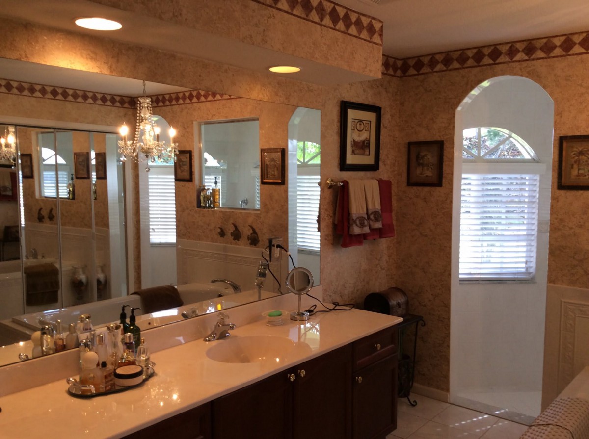 A well-decorated bathroom with a large mirror, chandelier, and neatly arranged towels.