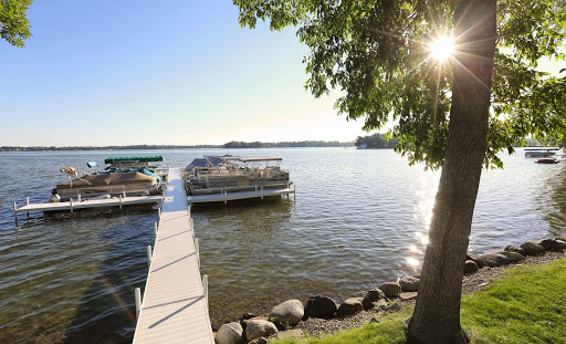 A peaceful lakeside view with a dock reaching out into the calm waters, illuminated by soft sunlight.
