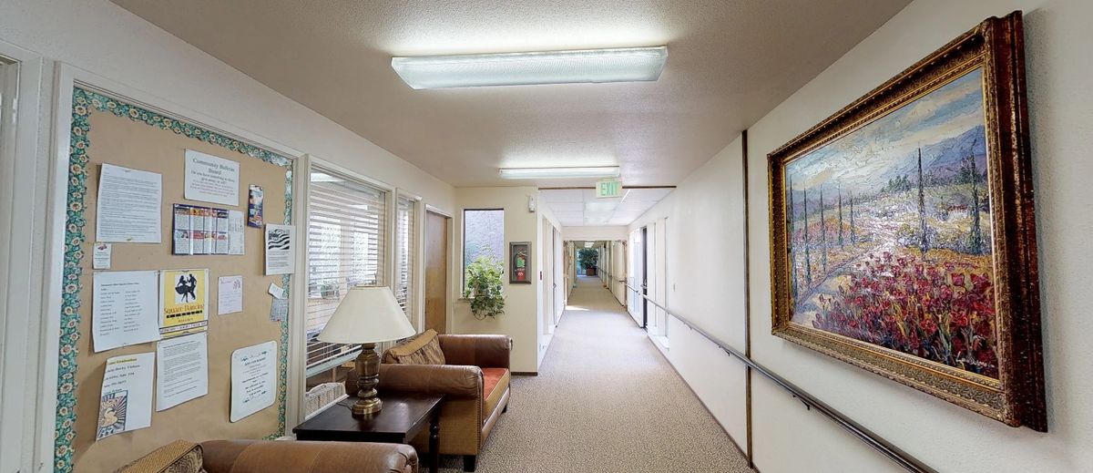 A well-lit hallway with office decor, featuring seating and fluorescent lights.
