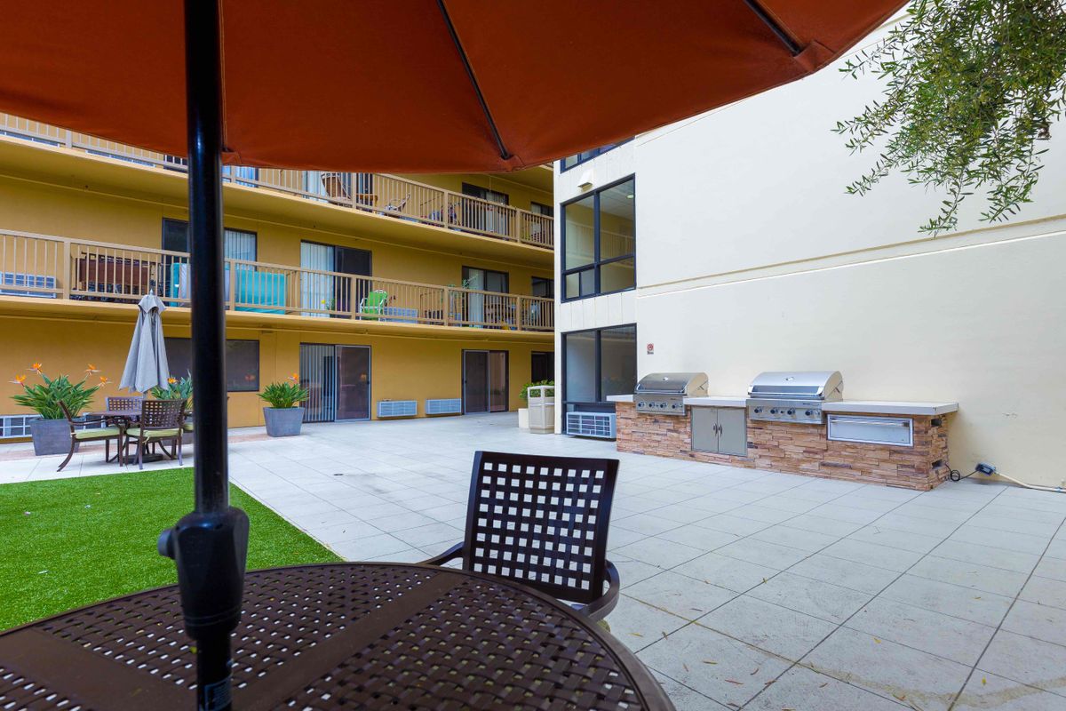 A modern apartment complex with an outdoor patio area featuring a table and umbrella.