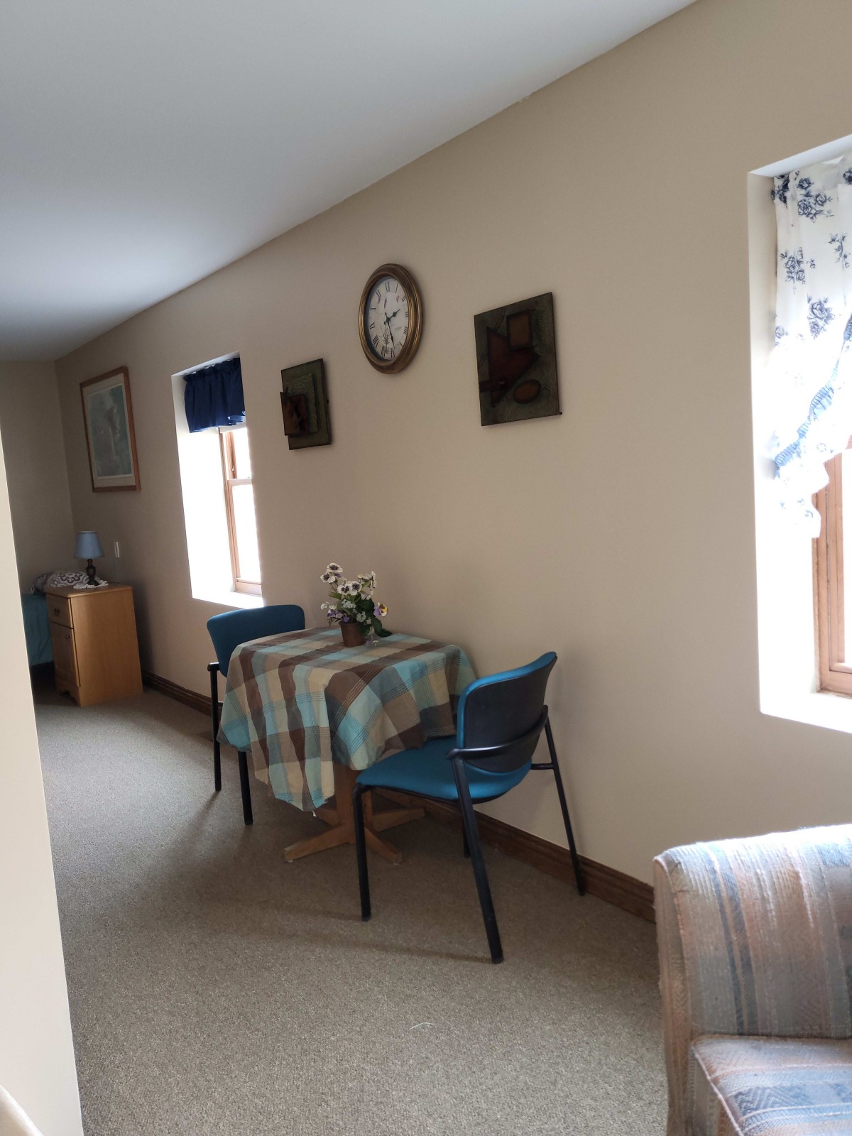 A cozy hallway with a small table and chairs, decorated with a clock and framed pictures on the wall.
