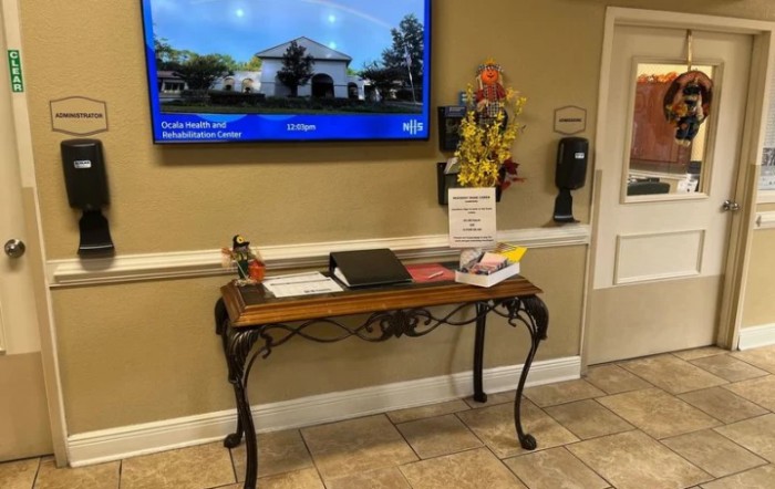 A reception area with a decorative table featuring sign-in materials and a television mounted on the wall above.