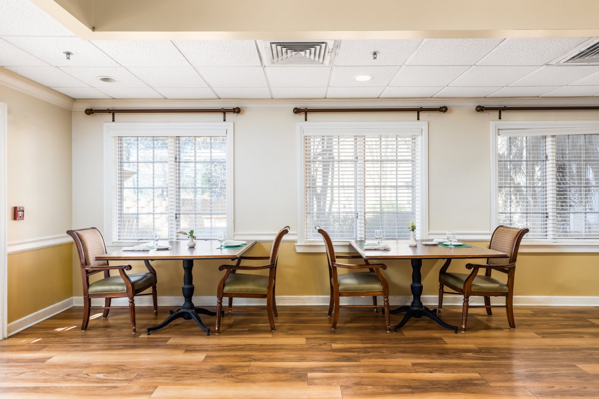 A cozy dining area with tables and chairs set by large windows.