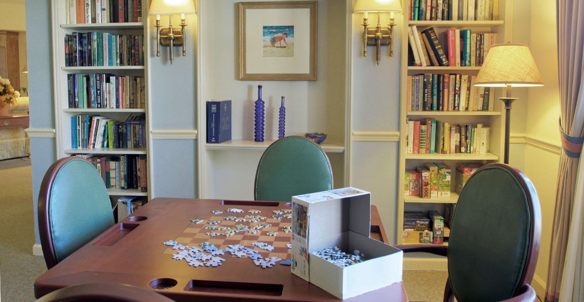 A cozy room with a puzzle in progress on the table and a bookshelf filled with books.