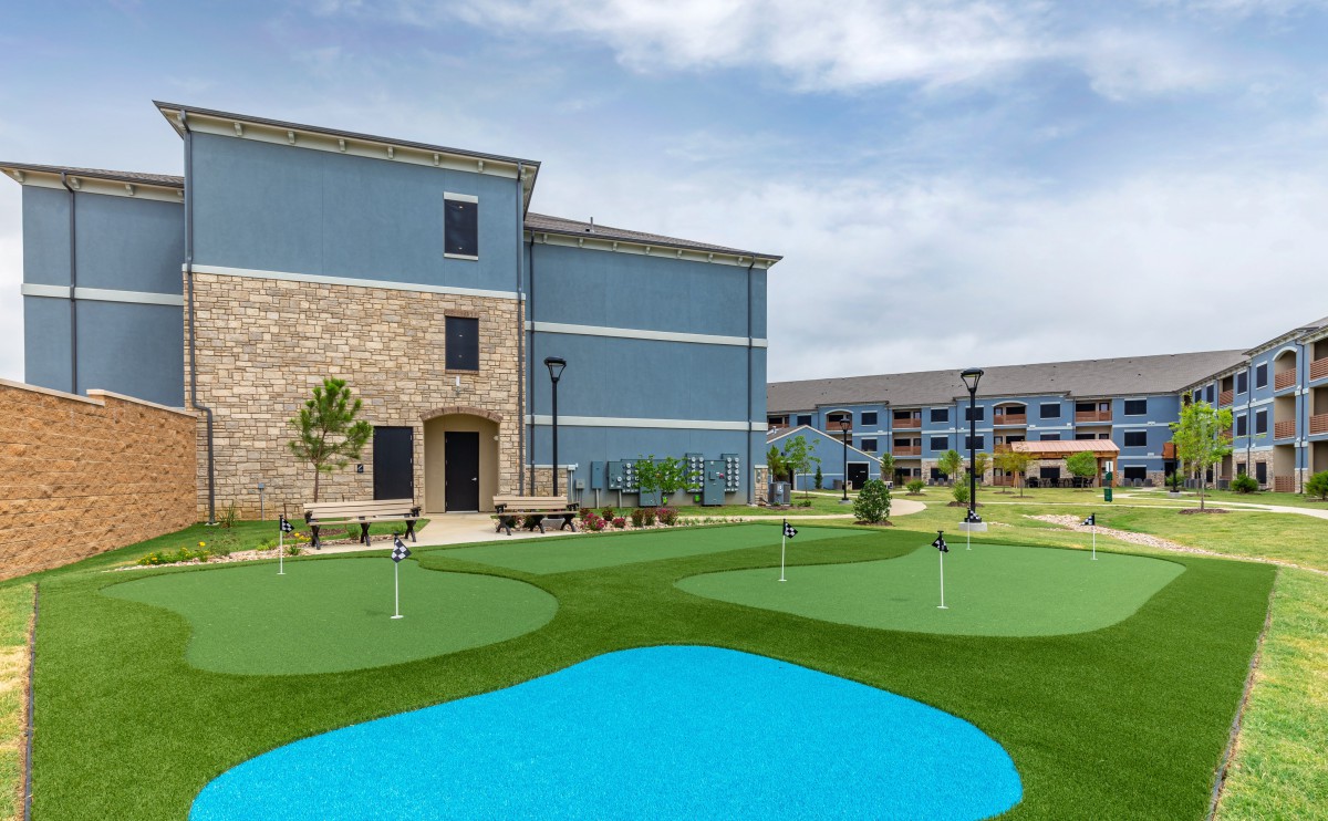 A residential complex featuring outdoor putting greens and modern architecture under a clear sky.