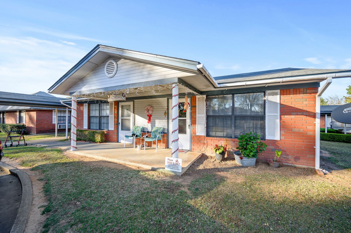 A suburban brick house with a front porch and yard.