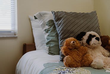 A cozy bed with plush pillows and cuddly stuffed animals.