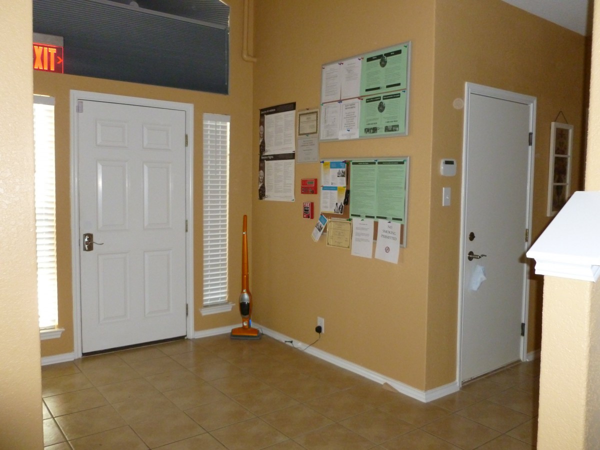 An organized entryway with a bulletin board and notices on the wall.