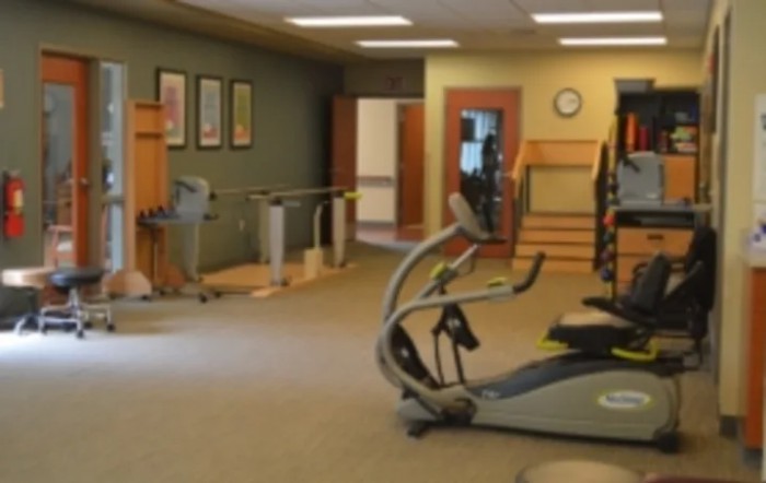 A gym with various exercise equipment and an open space for workouts.