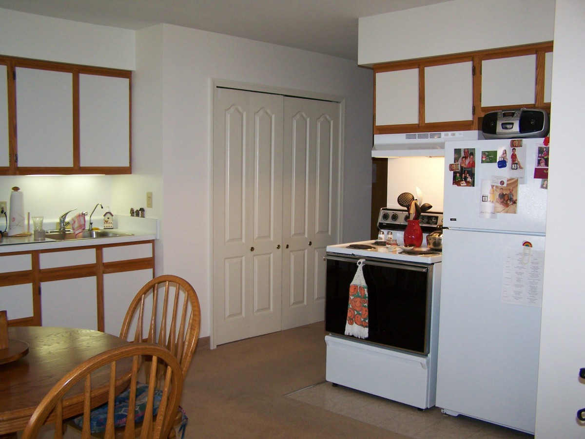 A cozy kitchen with a stove, dining table, and wooden cabinets.