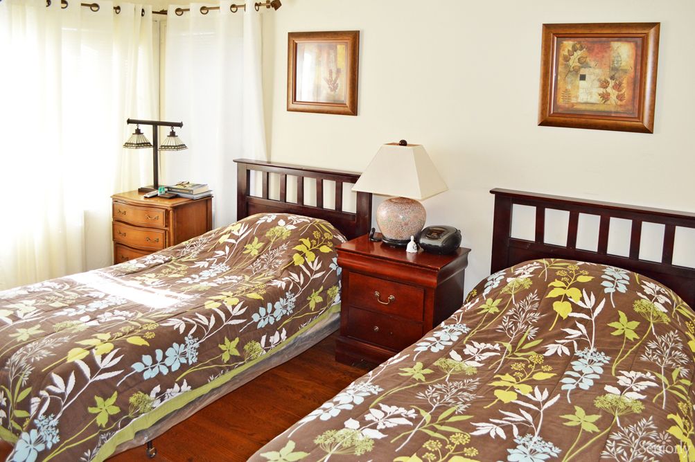 A cozy bedroom featuring twin beds with floral patterned covers, wooden furniture, and framed art on the walls.