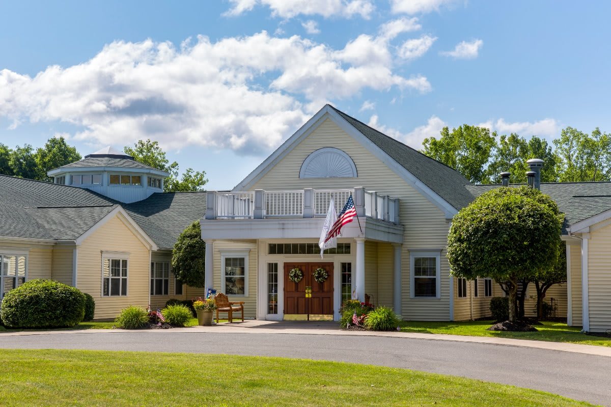A picturesque building with a flag and well-maintained lawn under a cloudy sky.
