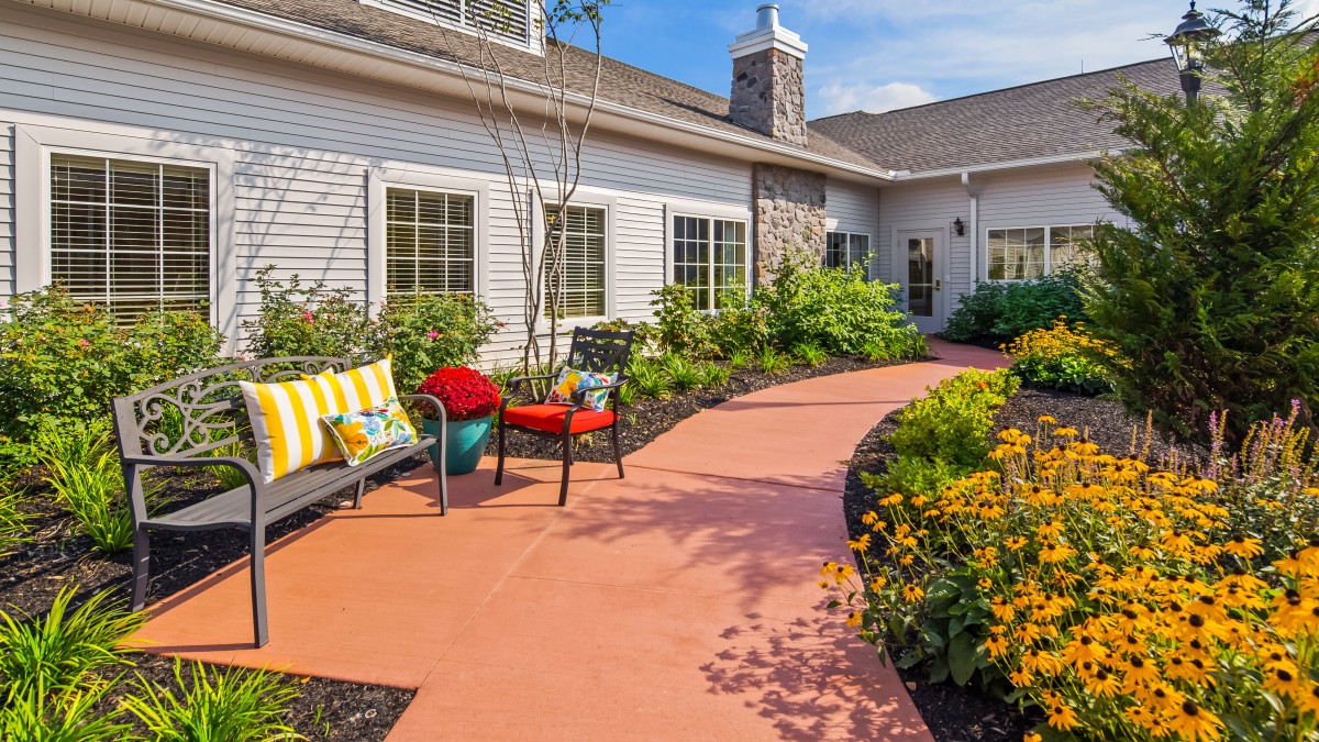 A charming garden patio with colorful seating and vibrant flowers lining the pathway.