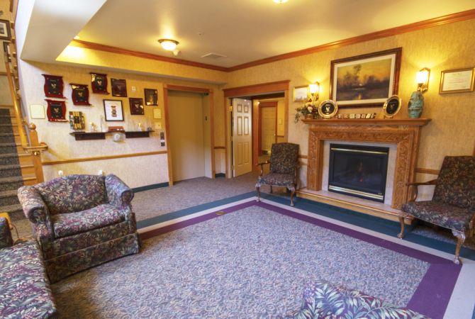A cozy living room featuring a warm fireplace, comfortable seating, and decorative artwork.