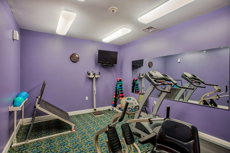A small indoor gym featuring exercise equipment against purple walls.