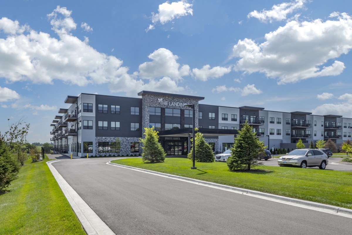 A modern apartment complex with well-maintained landscaping under a partly cloudy sky.