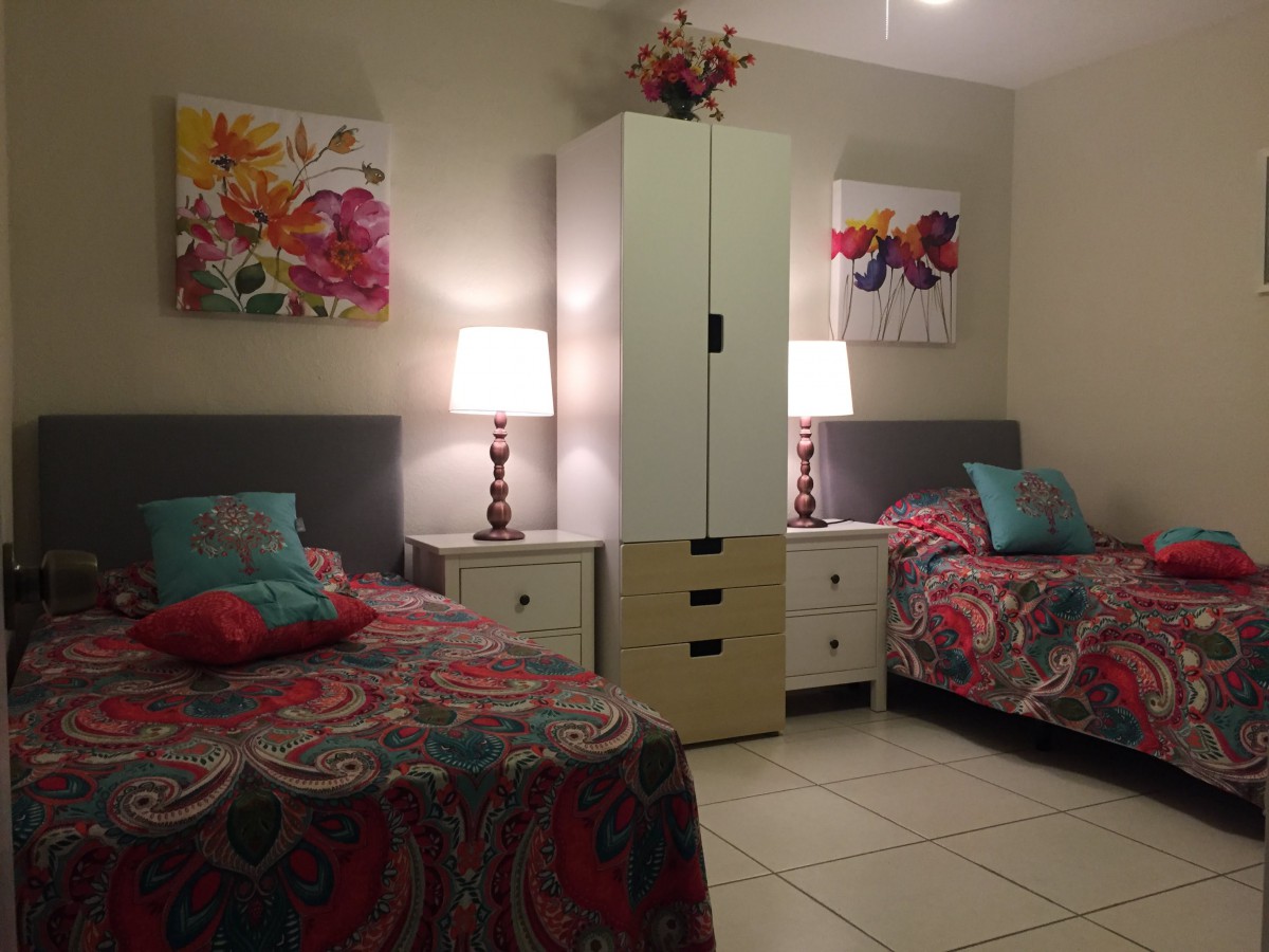 A cozy bedroom with twin beds adorned in colorful bedding and floral artwork.