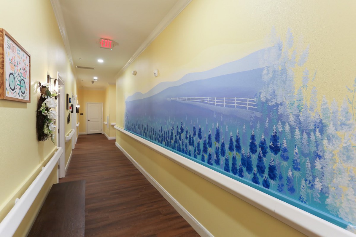 A well-lit hallway featuring a blue mural with wooden flooring.