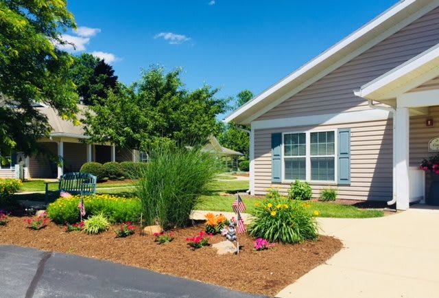 A well-maintained garden with colorful flowers and shrubs in front of a house.
