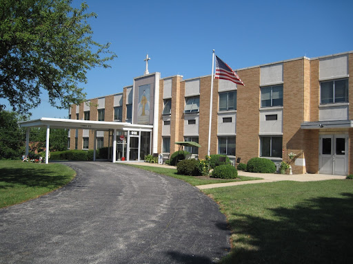 Exterior view of a hospital with an American flag, surrounded by greenery.
