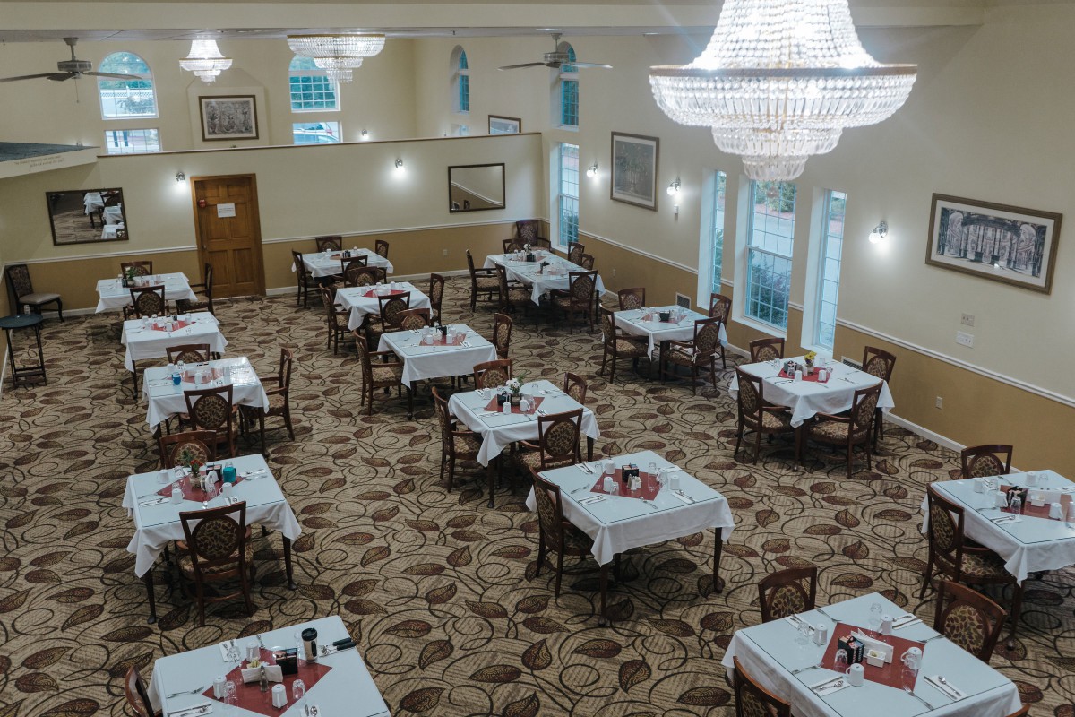 An elegantly decorated dining room with neatly arranged tables and chandeliers.