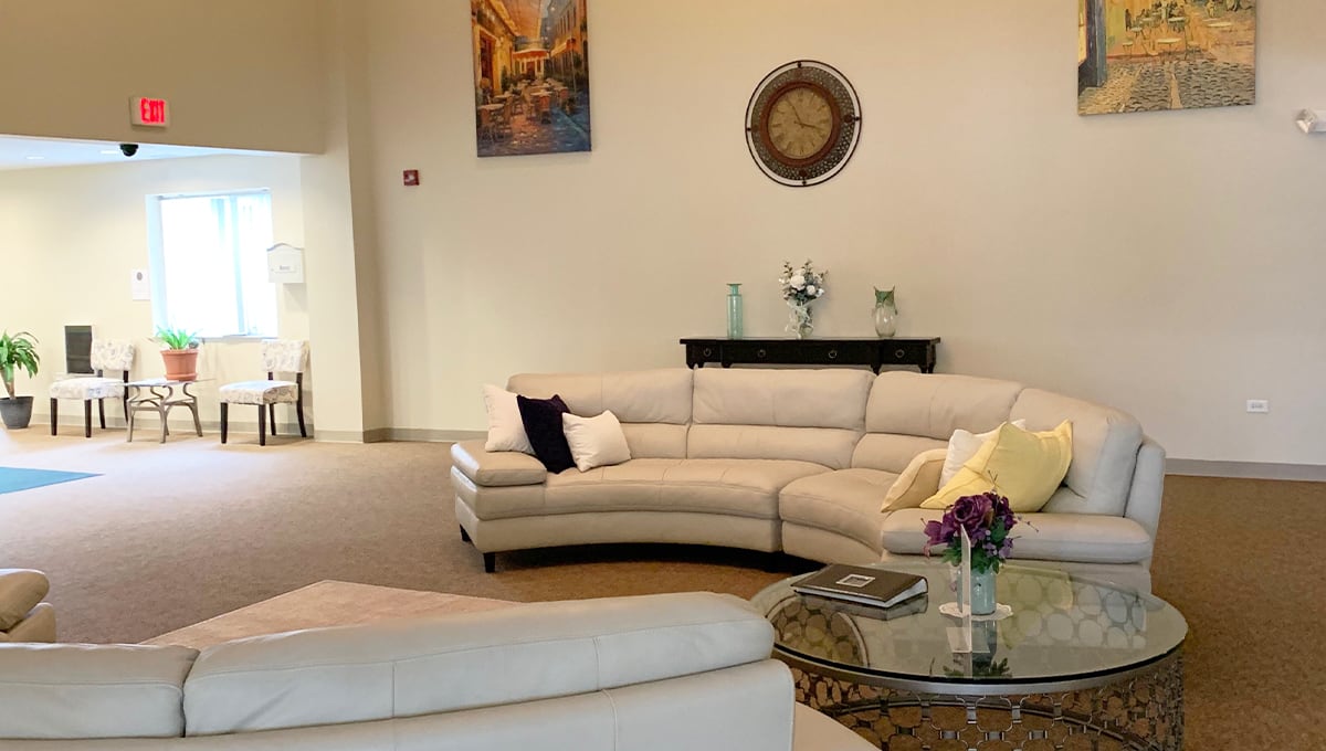 A stylish living room featuring a curved white sofa, decorative cushions, and wall art.