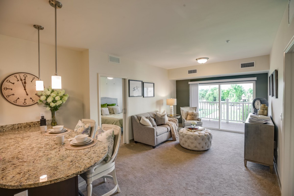 A spacious and elegantly designed living room with a dining area, featuring modern furniture and ample natural light.