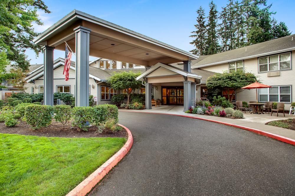 A welcoming building entrance with a covered driveway and landscaped surroundings.