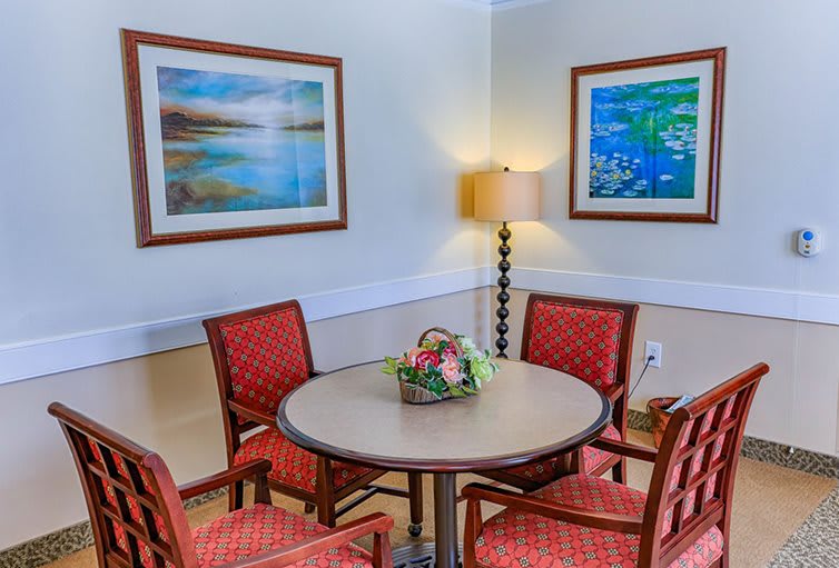 A cozy dining area with a round table surrounded by four chairs, adorned with colorful artwork and a decorative lamp.