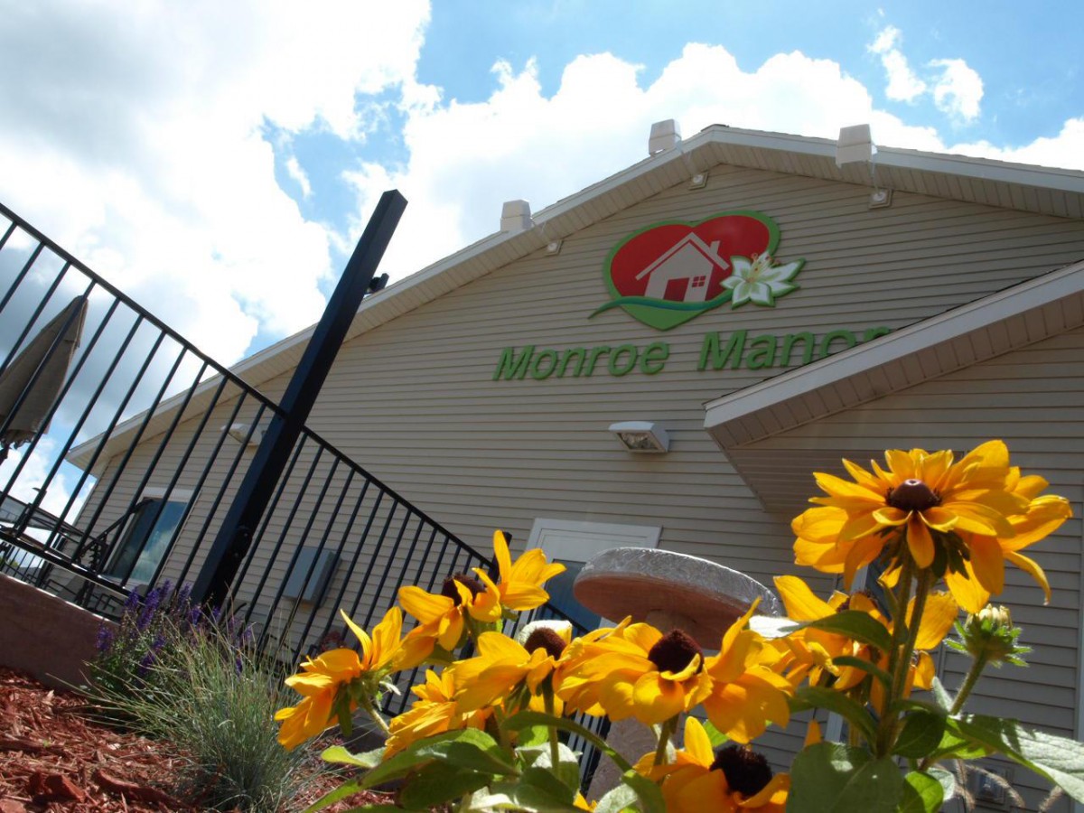 A sunny day at a building adorned with bright yellow flowers and a visible sign.