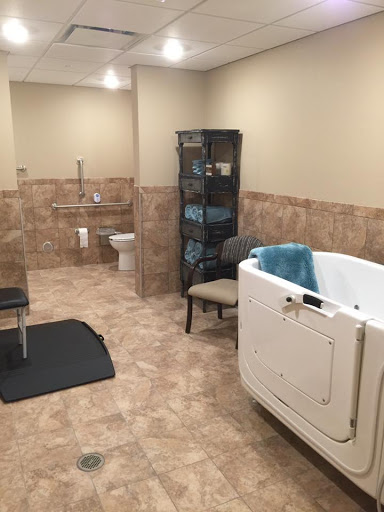 A spacious and accessible bathroom featuring a walk-in tub, tiled flooring, and a comfortable chair.