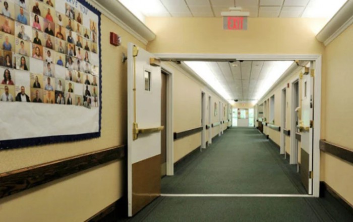 A long, illuminated hallway with doors on either side and a carpeted floor.