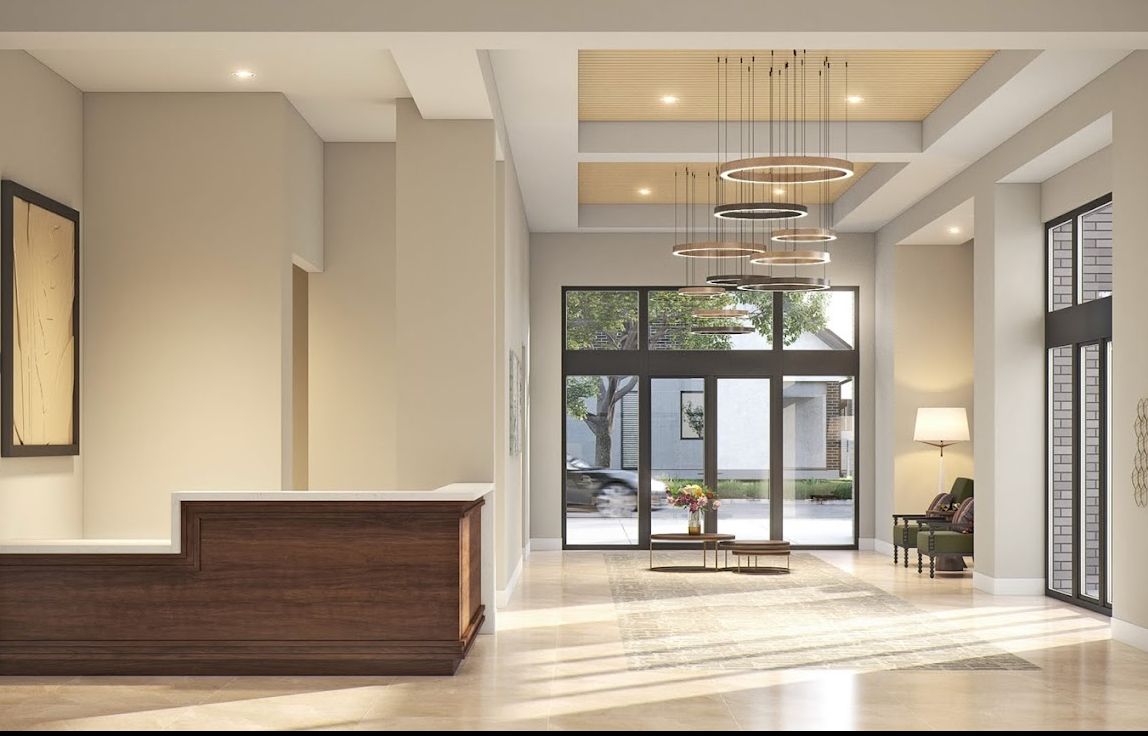 A modern and minimalist lobby with a reception desk, chandeliers, and large windows.