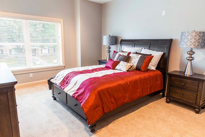 A cozy bedroom with a stylish bed and vibrant bedding.