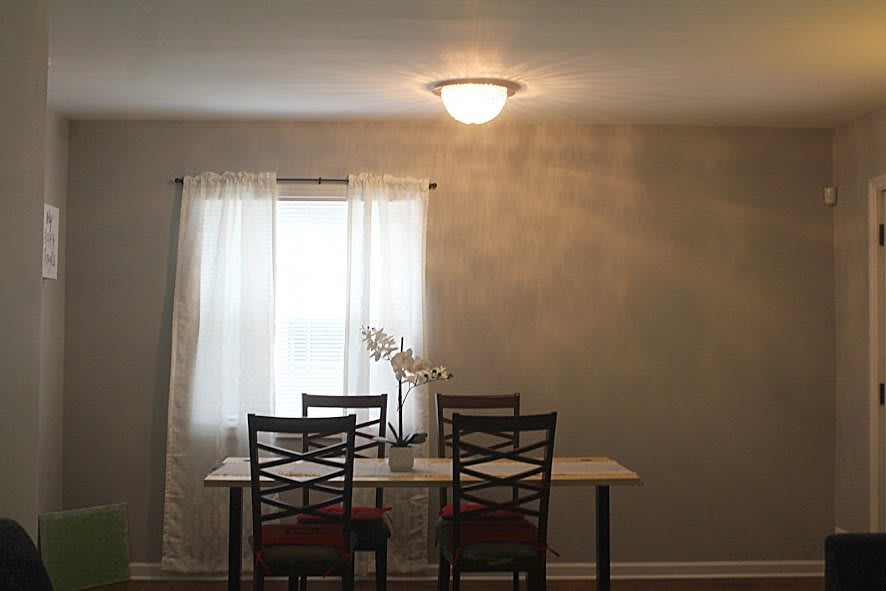 A minimalist dining room setup with a table and chairs by a window.