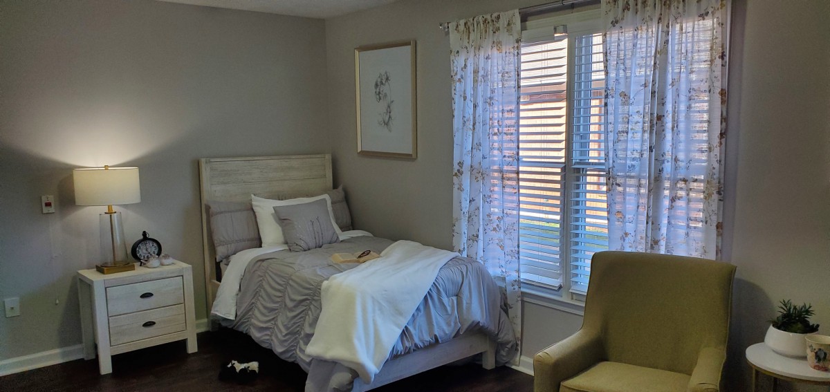 A cozy bedroom with a neatly made bed and natural light coming through a window.