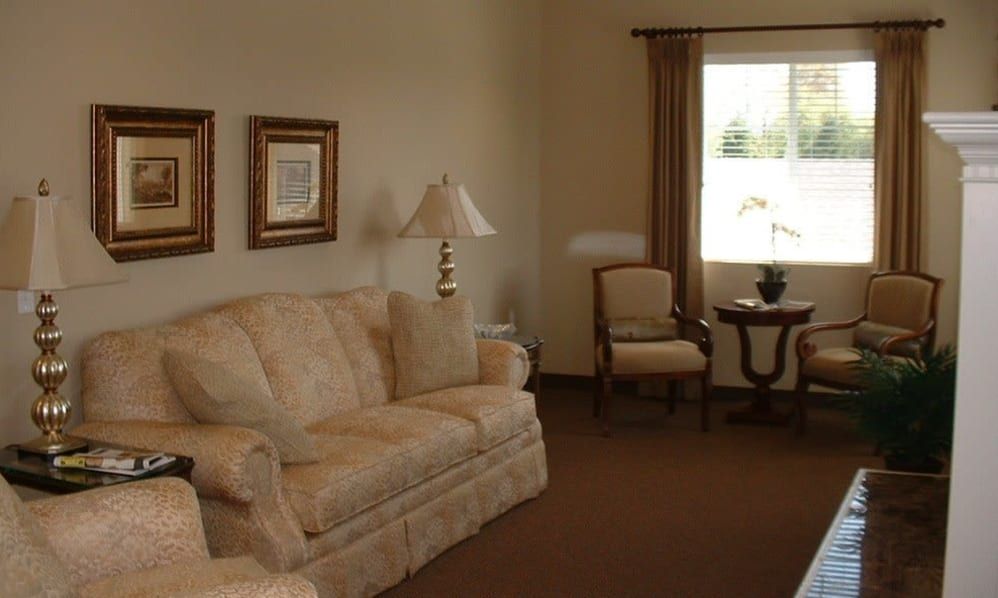 A cozy living room with a sofa, lamp, and window overlooking the outside.
