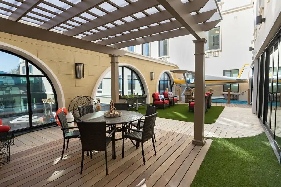 A stylish courtyard patio with a pergola, featuring comfortable outdoor furniture and a well-maintained lawn.